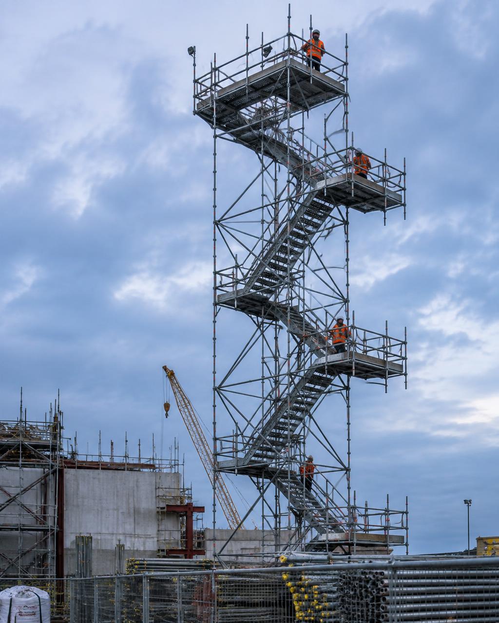 Steel scaffold tower with crews in hi-vis on a construction site